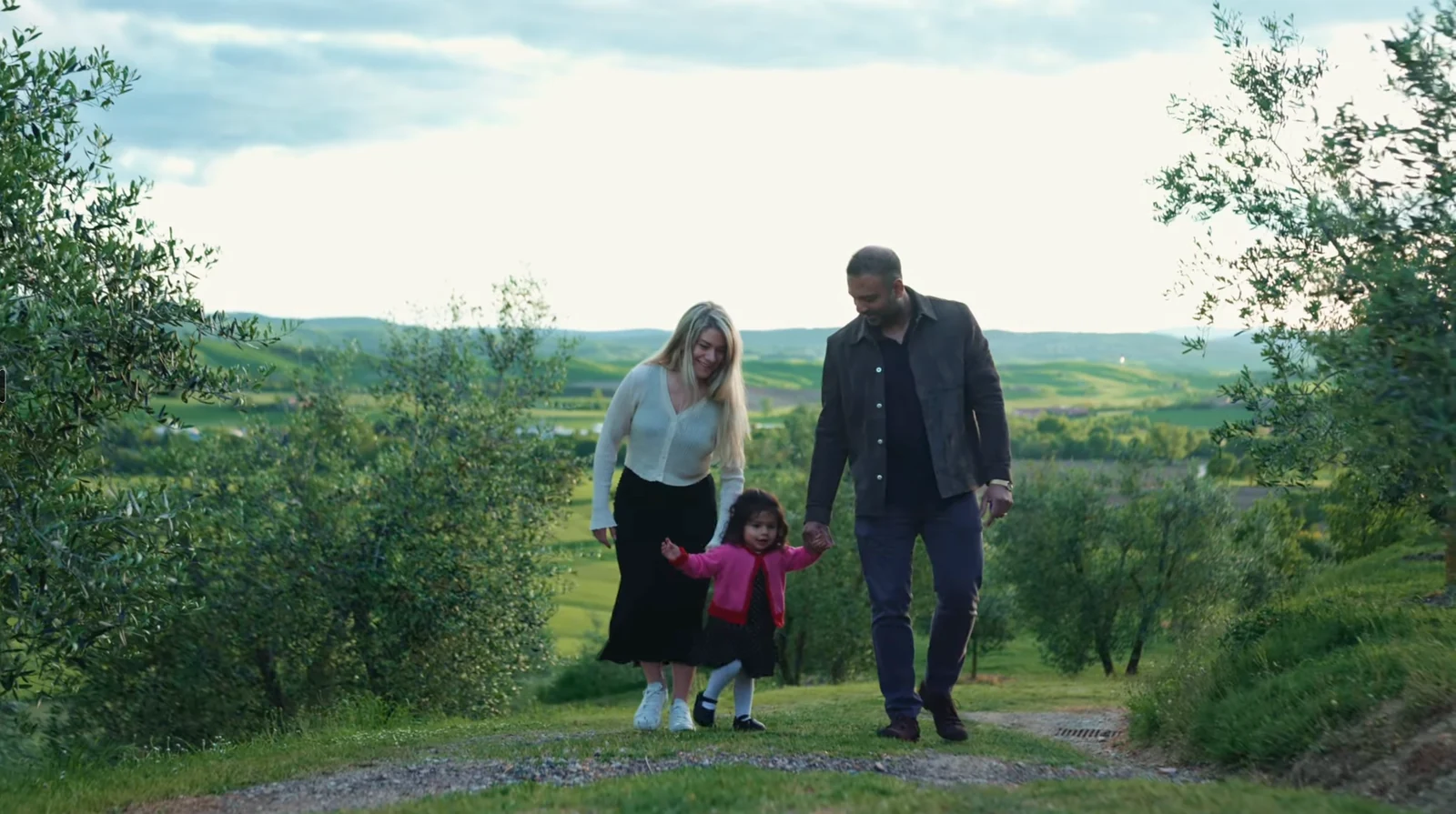 Rahul and Anna walking with their child through the Italian countryside